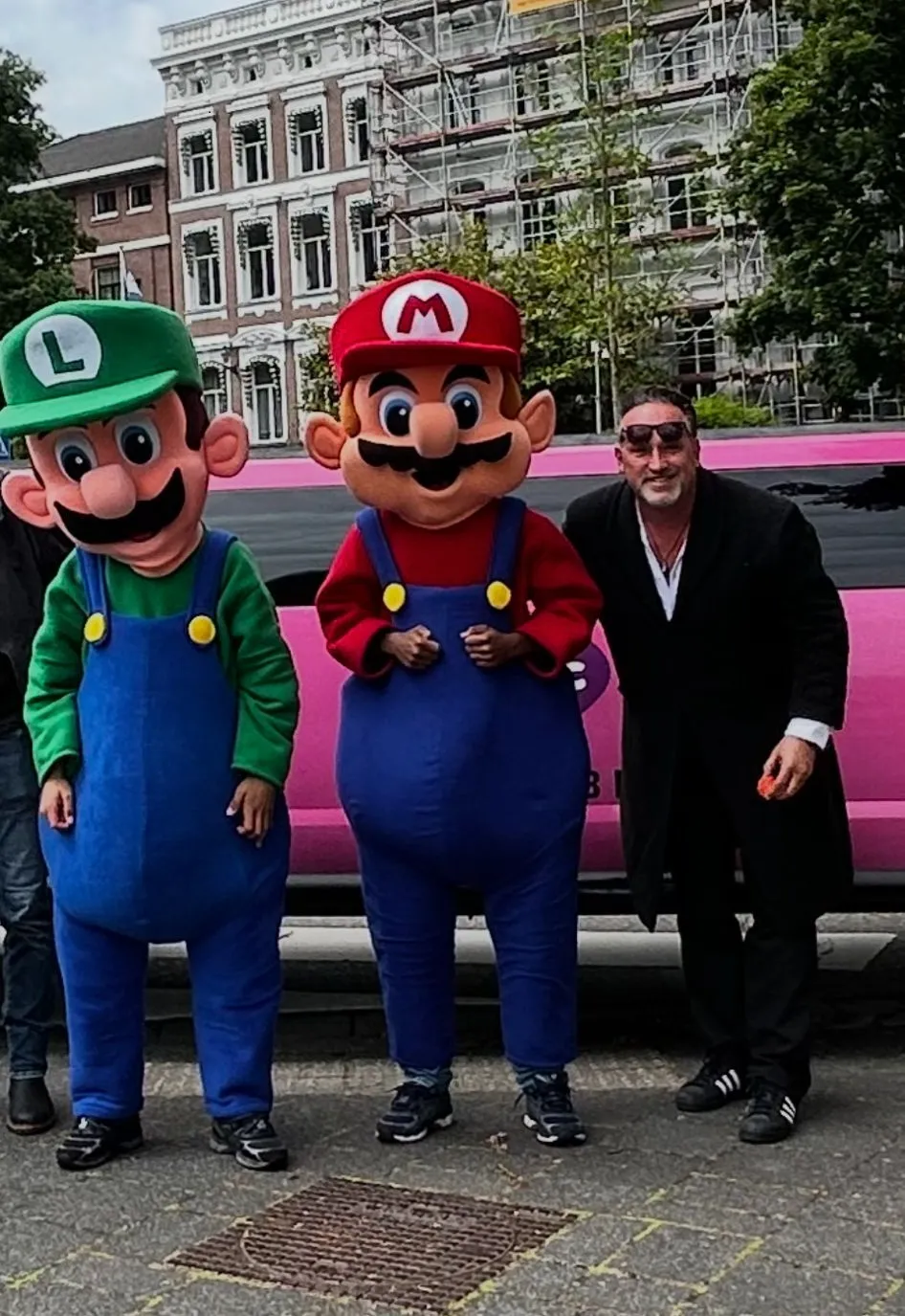 Chauffeur Frans met de Mario- en Luigi-mascottes bij de roze limousine